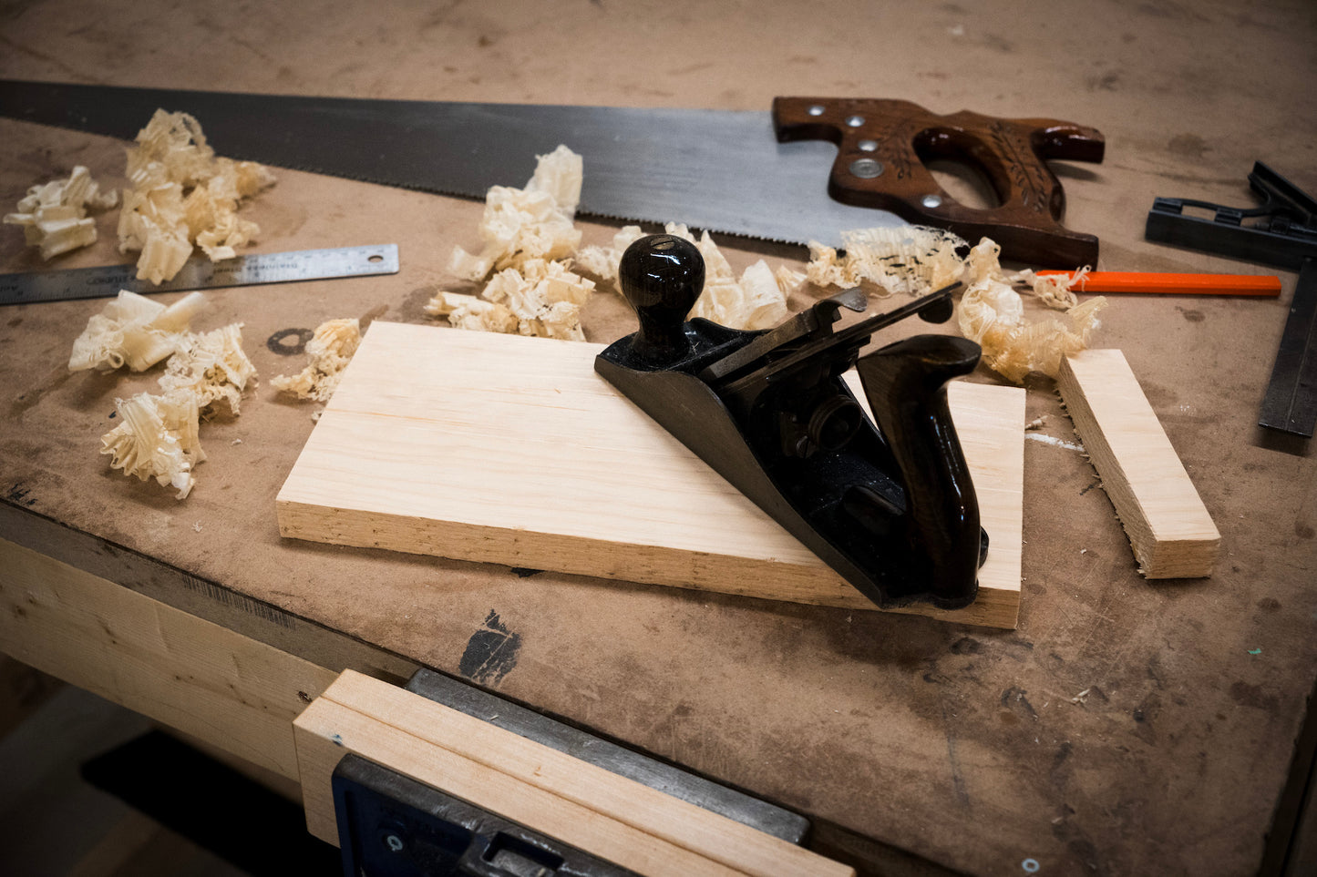 hand planer and saw besides a block of wood